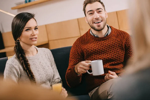 Selective focus of smiling friends looking at woman and chatting in cafe — Stock Photo