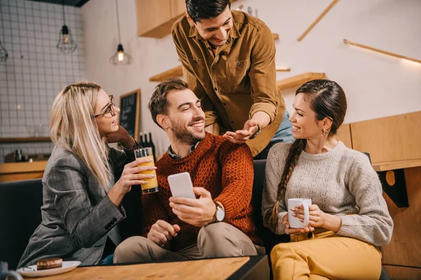 Heureux groupe d'amis souriant tout en tenant des boissons — Photo de stock