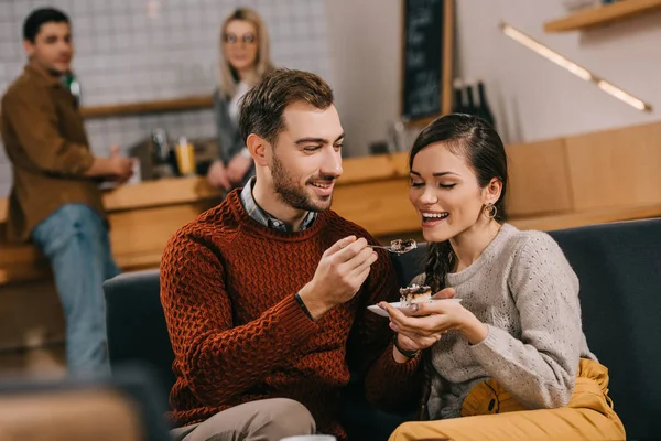 Messa a fuoco selettiva di bell'uomo che alimenta donna attraente con torta nel caffè — Foto stock