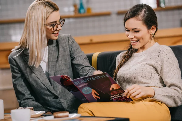 Attrayant femme dans des lunettes regarder ami lecture beauté magazine — Photo de stock