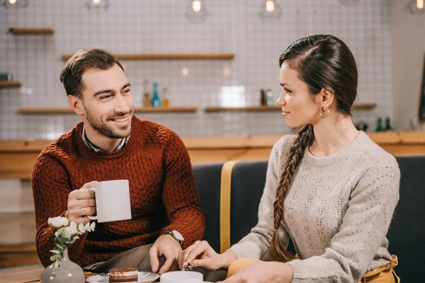 Handsome man looking at girlfriend while holding cup — Stock Photo