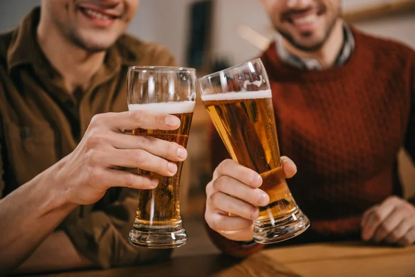Vista cortada de homens clinking com cerveja em óculos — Fotografia de Stock