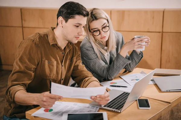 Mann und Frau schauen sich im Café Diagramme und Grafiken an — Stockfoto