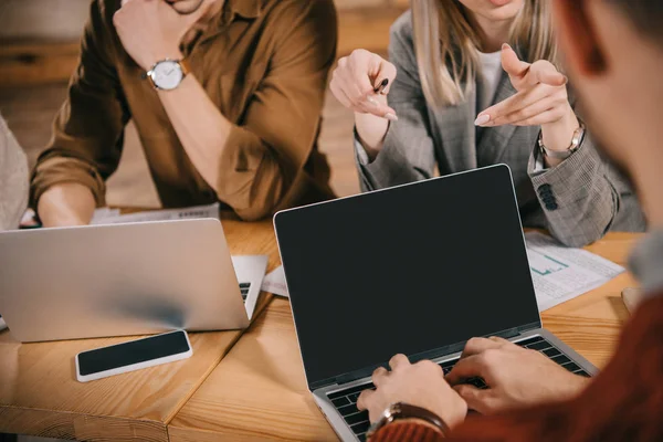 Cropped view of woman pointing with finger at coworker while talking in cafe — Stock Photo