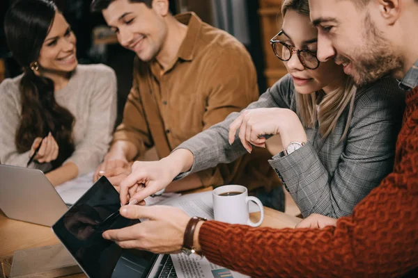 Selective focus of coworkers looking at laptop in cafe — Stock Photo