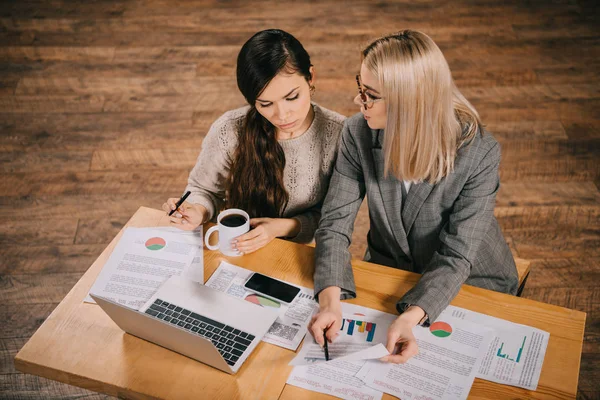 Donna attraente che mostra grafici e grafici al collega in caffè — Foto stock