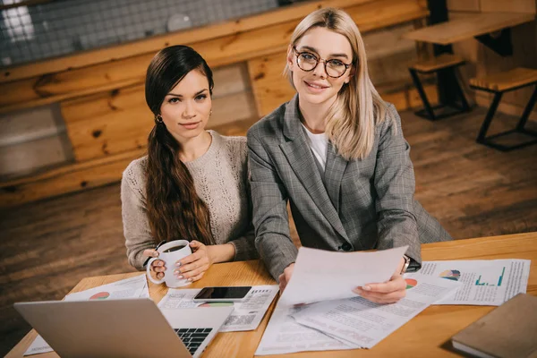 Attractive colleagues working in cafe near laptop — Stock Photo