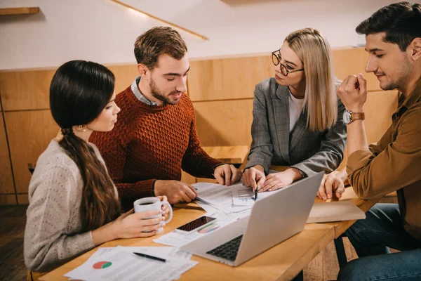 Group of coworkers looking at charts and graphs in cafe — Stock Photo