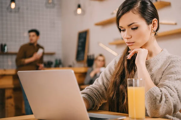 Selective focus of dreamy woman using laptop in cafe — Stock Photo