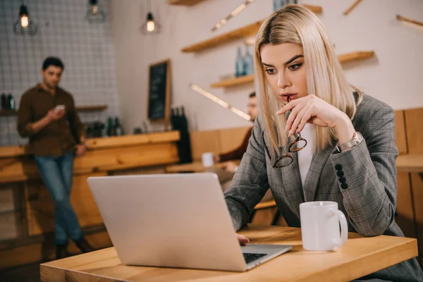 Messa a fuoco selettiva di donna premurosa guardando computer portatile in caffè — Foto stock