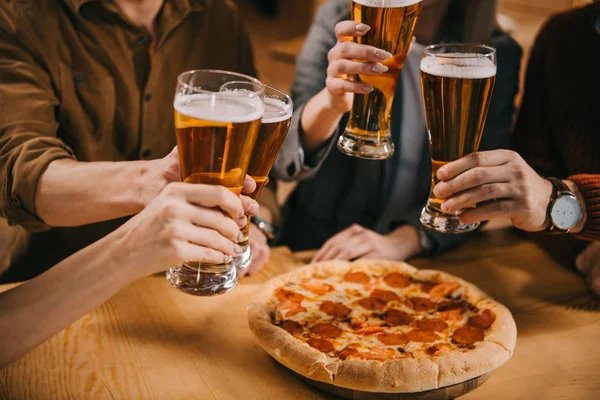 Vue recadrée d'amis griller des verres de bière dans le bar — Photo de stock