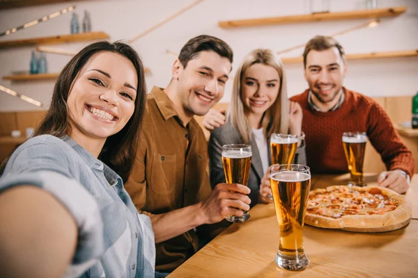 Selective focus of friends looking at camera and smiling in bar — Stock Photo