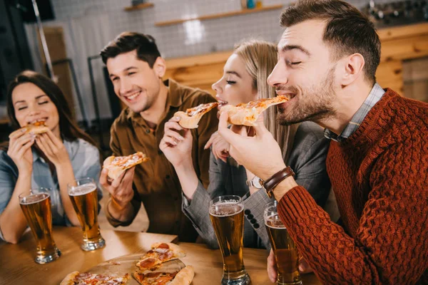 Enfoque selectivo de amigos felices comiendo pizza en el bar - foto de stock