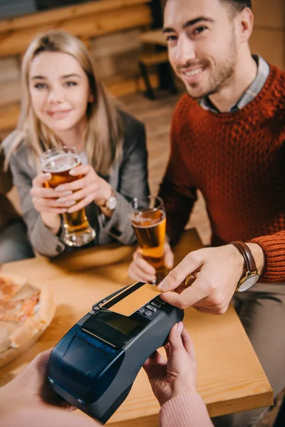 Foyer sélectif de l'homme payant par carte de crédit tout en caissier tenant terminal dans les mains — Photo de stock