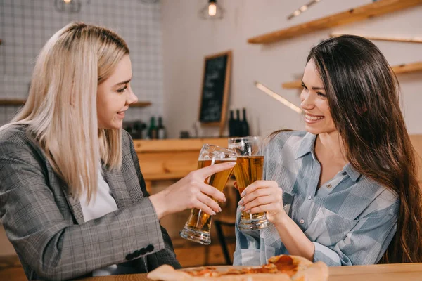 Mulheres bonitas sorrindo enquanto brindam copos de cerveja — Fotografia de Stock