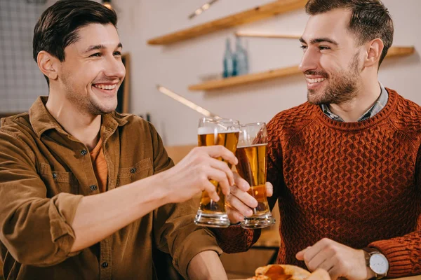 Uomini belli sorridenti mentre brindano bicchieri di birra — Foto stock