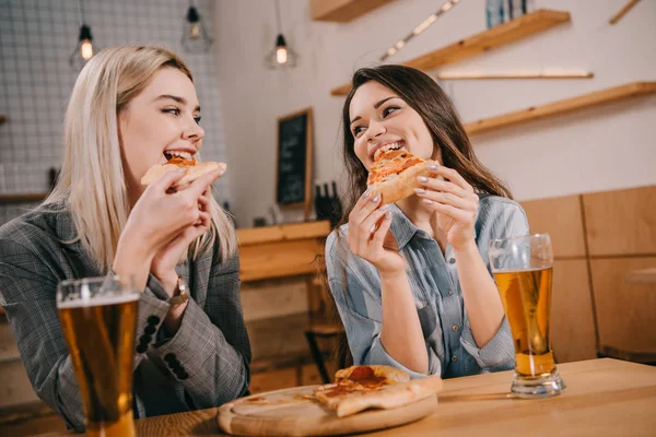 Amis gais manger une pizza savoureuse et regarder les uns les autres dans le bar — Photo de stock