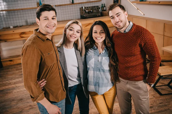 Glückliche Gruppe von Freunden lächelt und umarmt im Café — Stockfoto