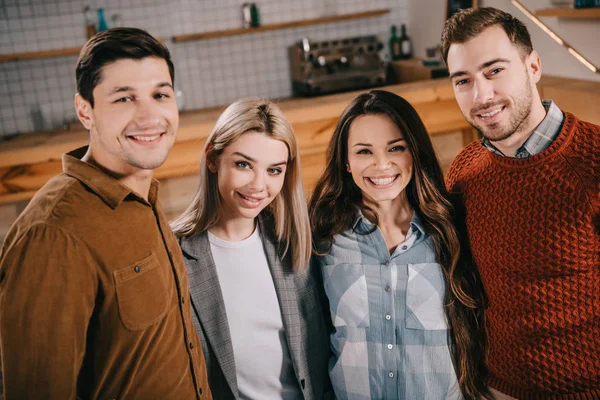 Happy group of friends smiling and hugging in cafe — Stock Photo