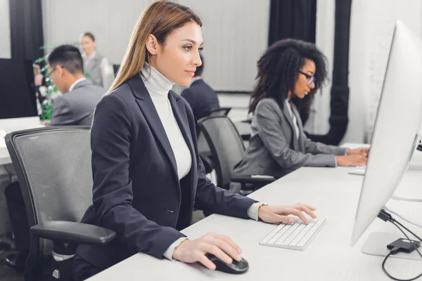 Seitenansicht einer fokussierten jungen Geschäftsfrau mit Desktop-Computer am Arbeitsplatz — Stockfoto