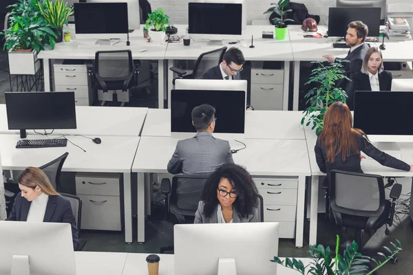 Hochwinkel-Ansicht multiethnischer Geschäftsleute, die mit Desktop-Computern im Großraumbüro arbeiten — Stockfoto