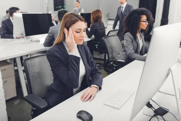 Jovem empresária em desgaste formal que sofre de dor de cabeça no local de trabalho — Fotografia de Stock