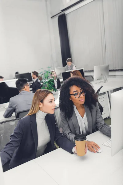 Visão de alto ângulo de belas mulheres de negócios multiétnicas usando computador desktop juntos no escritório — Fotografia de Stock