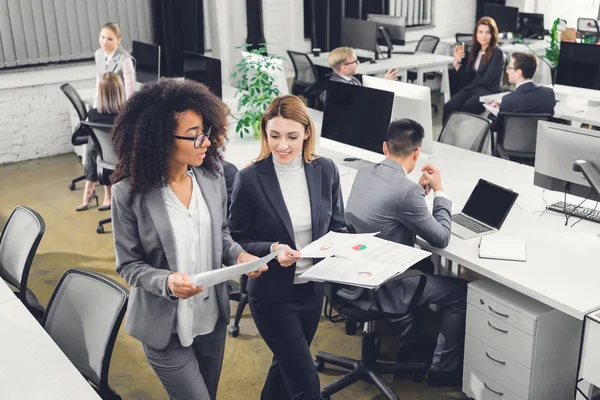 Blick aus der Vogelperspektive auf professionelle junge multiethnische Geschäftsfrauen, die Dokumente in der Hand halten und das Projekt im Amt diskutieren — Stockfoto