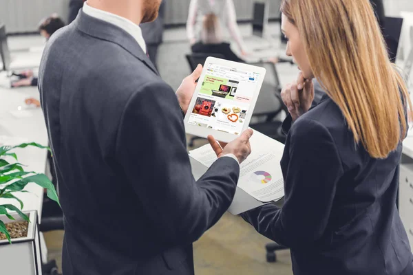 Plan recadré de jeunes collègues d'affaires concentrés utilisant une tablette numérique avec application ebay au bureau — Photo de stock