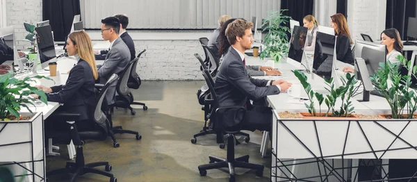 Professional young businesspeople working with desktop computers in open space office — Stock Photo