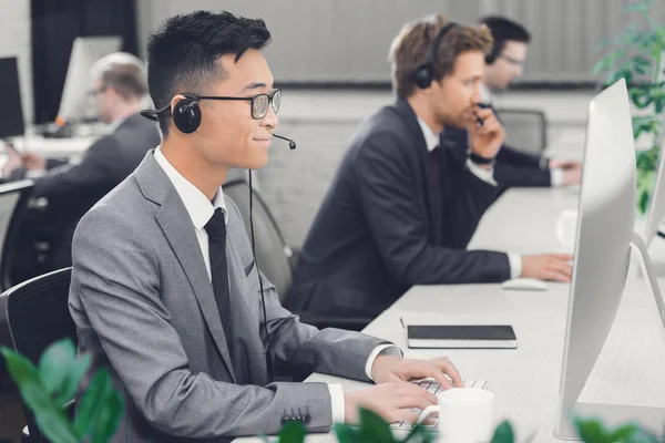 Visão lateral de jovens operadores de call center do sexo masculino trabalhando juntos no escritório — Fotografia de Stock