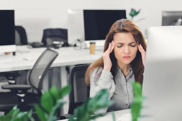 Joven mujer de negocios que sufre de dolor de cabeza mientras trabaja en el cargo - foto de stock