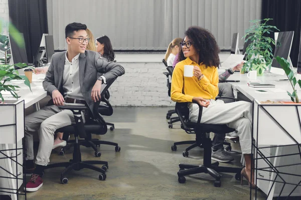 Happy young multiethnic businesspeople smiling each other while working together in office — Stock Photo