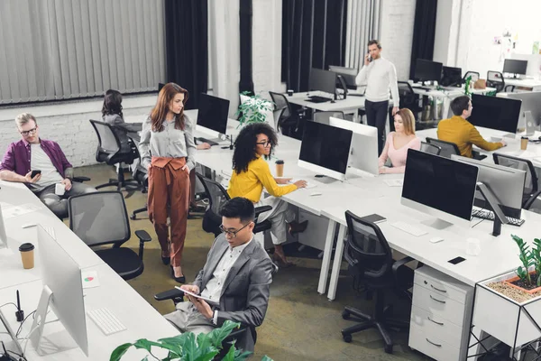 Vista de ángulo alto de los jóvenes empresarios multiétnicos profesionales que trabajan en la oficina de espacio abierto — Stock Photo