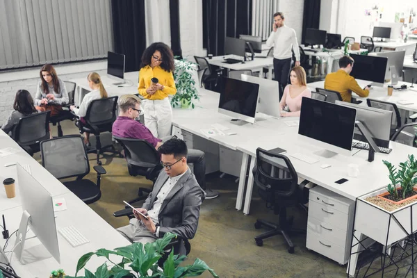 Blick aus der Vogelperspektive auf die multiethnische Gruppe von Geschäftsleuten, die im Großraumbüro zusammenarbeiten — Stockfoto
