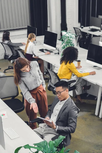 Vista de ángulo alto de los jóvenes empresarios profesionales que discuten el trabajo en la oficina de espacio abierto - foto de stock