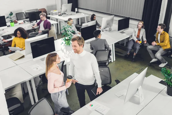 Vue en grand angle de jeunes collègues d'affaires professionnels parlant et travaillant dans un bureau à aire ouverte — Photo de stock