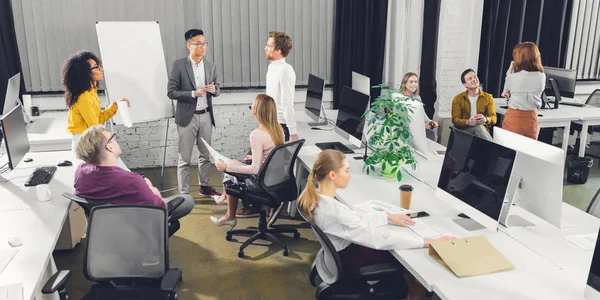 Vista de ángulo alto de profesionales jóvenes empresarios multirraciales que trabajan juntos en la oficina de espacio abierto - foto de stock