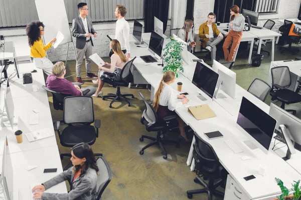 Vista de ángulo alto de los jóvenes empresarios profesionales que trabajan juntos en la oficina de espacio abierto - foto de stock