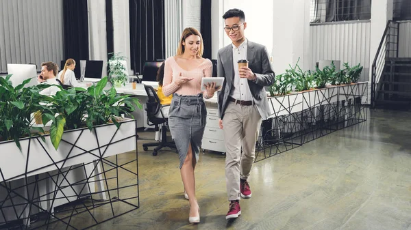 Heureux professionnels jeunes collègues d'affaires en utilisant la tablette numérique et la marche dans le bureau — Photo de stock