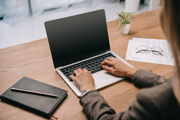 Visão cortada de empresária digitando no laptop no local de trabalho com documentos — Fotografia de Stock