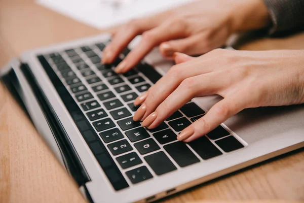 Vista parcial de la mujer de negocios escribiendo en el ordenador portátil en el lugar de trabajo - foto de stock