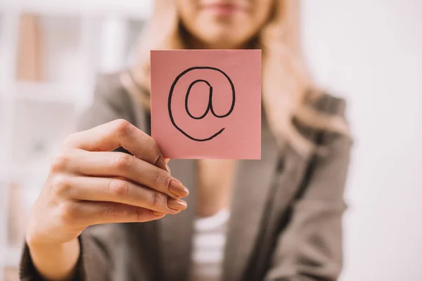 Partial view of businesswoman holding paper note with email symbol — Stock Photo