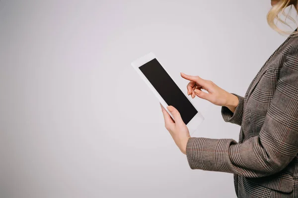 Обрезанный взгляд на деловую женщину с помощью цифрового планшета, изолированного на сером с чистым экраном — стоковое фото