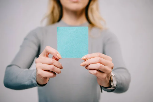 Vista ritagliata di donna in possesso di carta blu vuota nota isolata su grigio — Foto stock