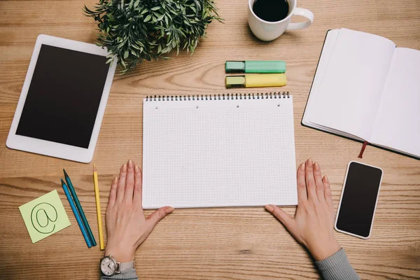 Cropped view of businesswoman with digital devices and notebooks at workplace — Stock Photo