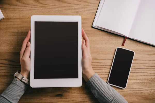 Vista recortada de la mujer de negocios que sostiene la tableta digital en el lugar de trabajo con teléfono inteligente y portátil - foto de stock