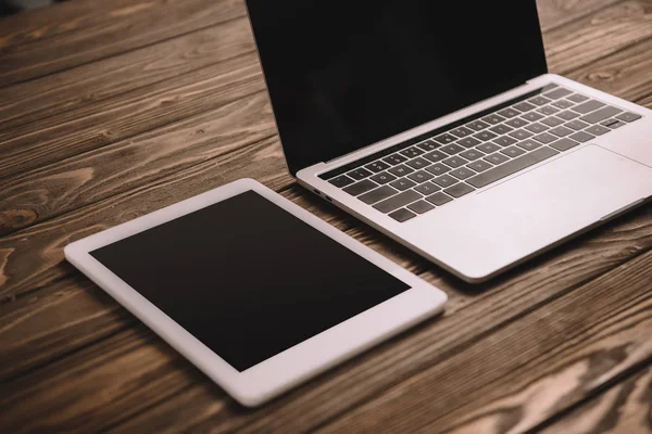 Tableta digital y portátil con pantallas en blanco en la mesa de madera — Stock Photo