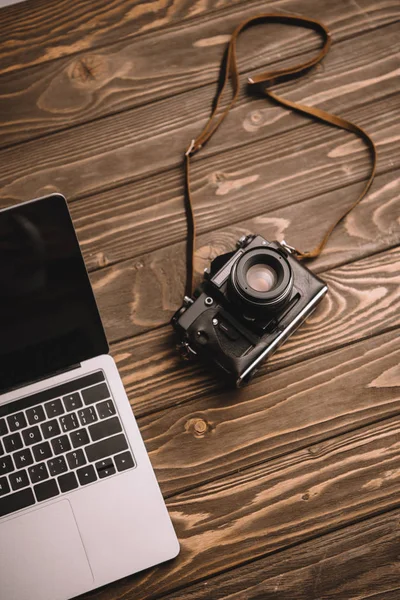 Laptop e câmera de foto retro na mesa de madeira — Fotografia de Stock
