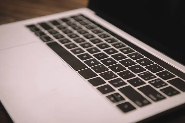 Primo piano di tastiera di computer portatile su posto di lavoro di legno — Foto stock